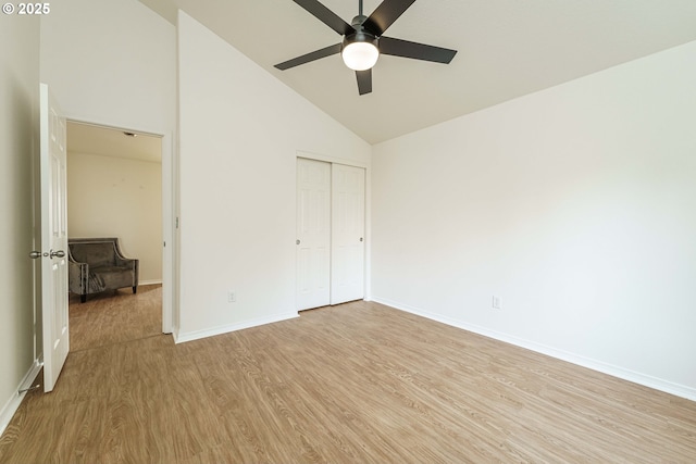 unfurnished bedroom with high vaulted ceiling, a closet, ceiling fan, and light wood-type flooring