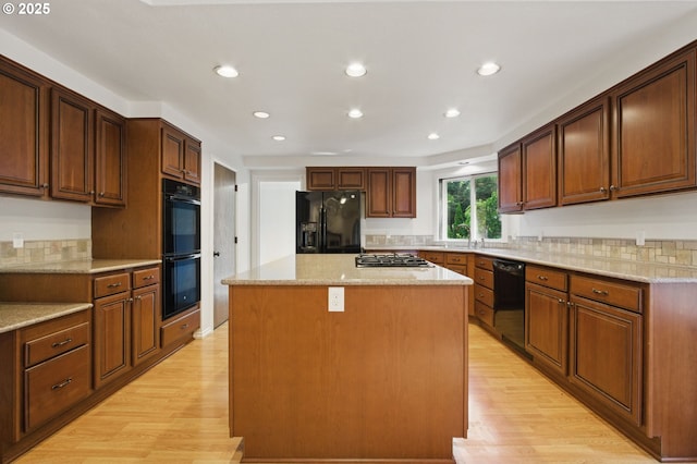 6765 SW 153rd Ave, Beaverton, OR 97007 - kitchen with black appliances, light wood finished floors, recessed lighting, a center island, and light stone countertops