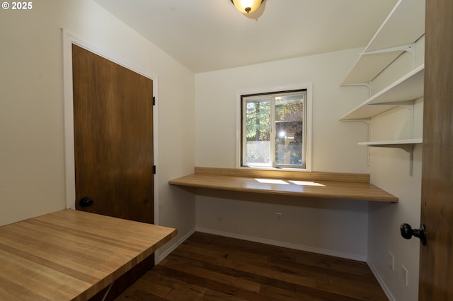 unfurnished office featuring baseboards and dark wood finished floors