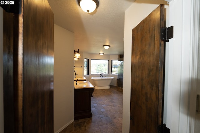 hall featuring a sink, stone finish flooring, and a textured ceiling