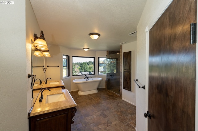 full bath with a sink, double vanity, stone finish floor, a shower stall, and a soaking tub