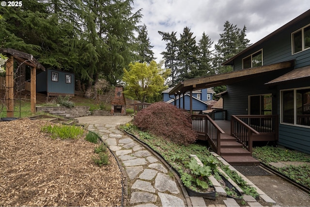view of yard featuring a fireplace, a wooden deck, and an outdoor structure