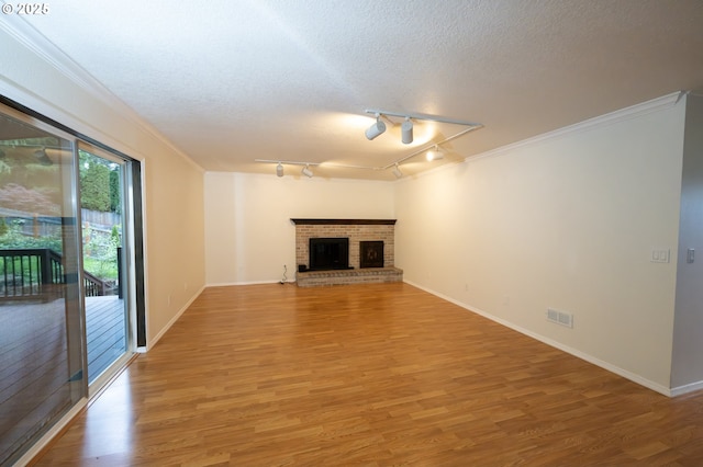6765 SW 153rd Ave, Beaverton, OR 97007 - unfurnished living room featuring light wood finished floors, crown molding, baseboards, a textured ceiling, and rail lighting