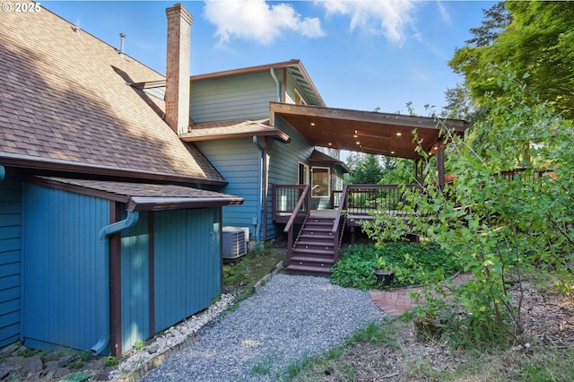 6765 SW 153rd Ave, Beaverton, OR 97007 - back of house featuring a chimney, a shingled roof, a wooden deck, and cooling unit