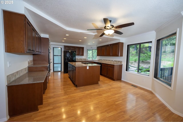 6765 SW 153rd Ave, Beaverton, OR 97007 - kitchen with black appliances, a kitchen island, a ceiling fan, light wood-style floors, and a textured ceiling