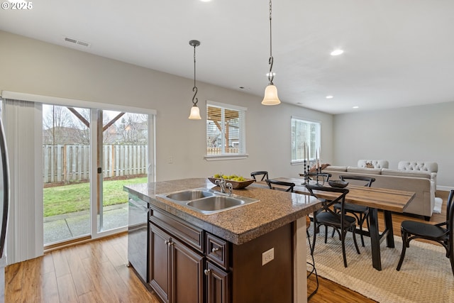 kitchen with dishwasher, sink, hanging light fixtures, a center island with sink, and dark brown cabinets