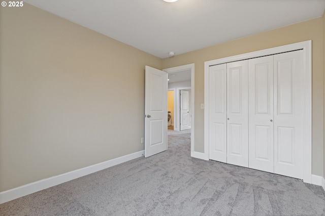 unfurnished bedroom featuring light carpet and a closet