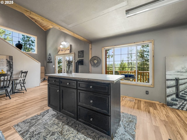 kitchen featuring dark cabinetry, light wood-style flooring, a textured ceiling, and a center island