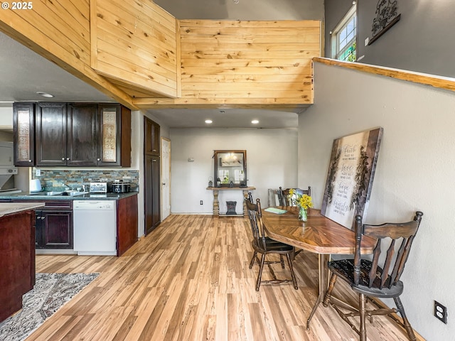 kitchen with dishwasher, light wood-style floors, decorative backsplash, recessed lighting, and glass insert cabinets