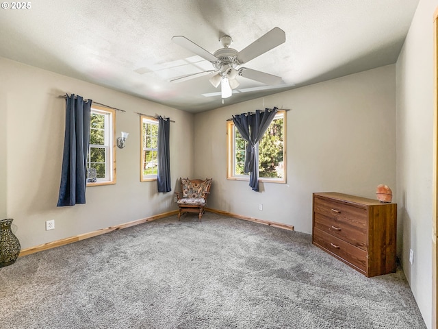 carpeted spare room with ceiling fan, baseboards, and a textured ceiling