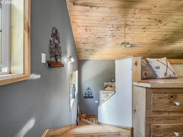 stairway featuring wooden ceiling, lofted ceiling, and baseboards