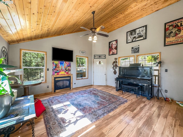 living room featuring wood ceiling, wood-type flooring, a glass covered fireplace, a ceiling fan, and vaulted ceiling