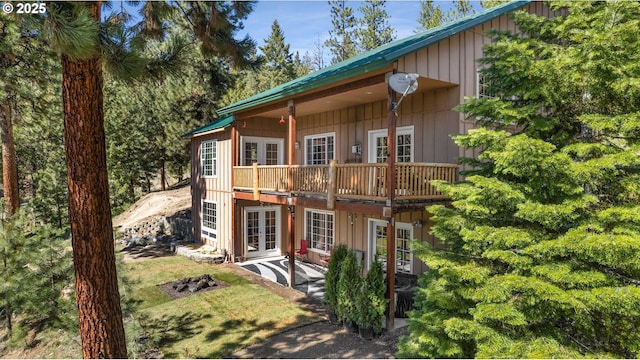 back of property with french doors and board and batten siding