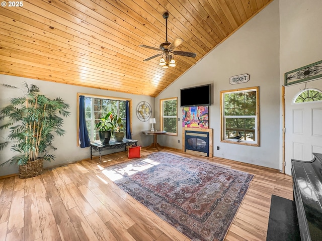 living room featuring wooden ceiling, a glass covered fireplace, a ceiling fan, wood finished floors, and high vaulted ceiling