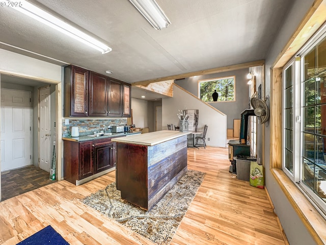 kitchen featuring light wood finished floors, decorative backsplash, a center island, and dark brown cabinets
