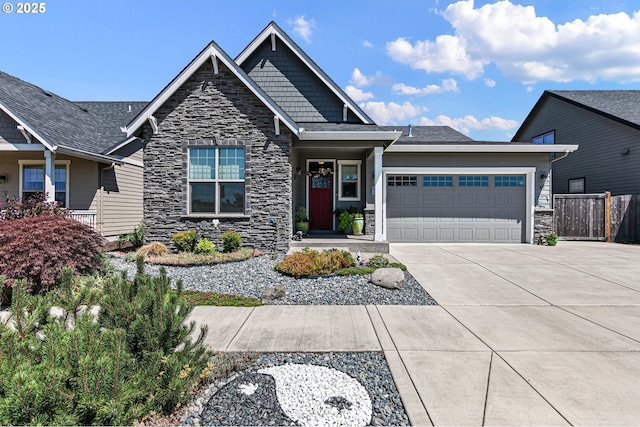 craftsman-style home featuring an attached garage, fence, driveway, and stone siding