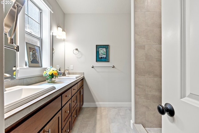 full bath featuring baseboards, a sink, tile patterned floors, and double vanity