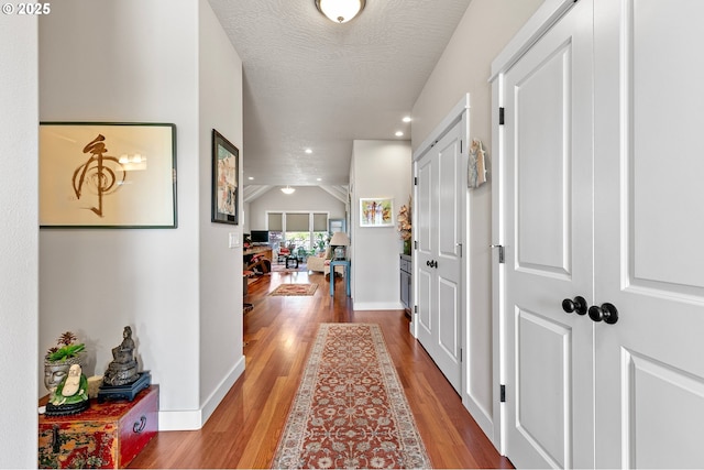 hallway with recessed lighting, baseboards, wood finished floors, and a textured ceiling