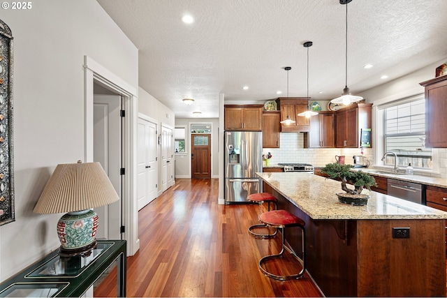 kitchen with backsplash, a center island, wood finished floors, stainless steel appliances, and a wealth of natural light