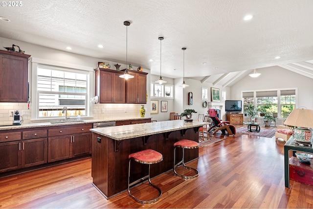 kitchen with a kitchen island, a sink, open floor plan, a breakfast bar, and light wood-style flooring