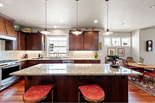 kitchen featuring a sink, appliances with stainless steel finishes, a textured ceiling, and dark wood-type flooring