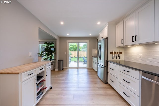 kitchen featuring stainless steel appliances, decorative backsplash, white cabinetry, light wood finished floors, and recessed lighting