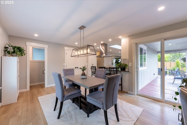 dining area with light wood-style flooring, baseboards, recessed lighting, and a chandelier