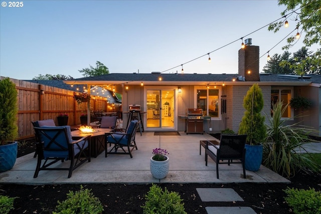 back of property featuring an outdoor fire pit, a chimney, fence, and a patio area
