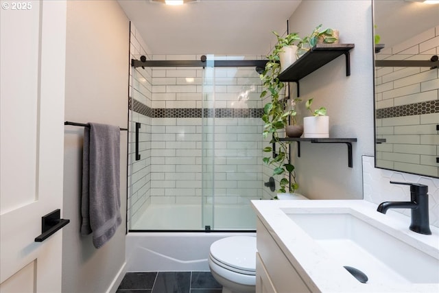 full bath with toilet, vanity, and bath / shower combo with glass door
