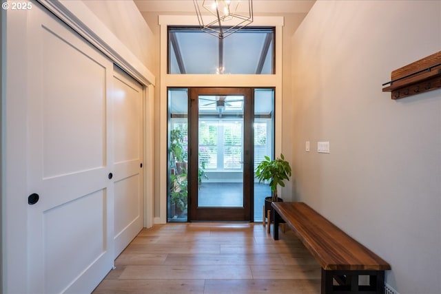 foyer entrance with a chandelier, light wood finished floors, and baseboards