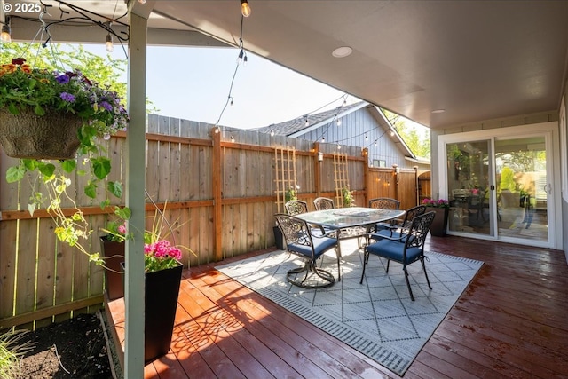 wooden terrace with outdoor dining area and fence