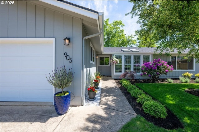doorway to property with a garage and a yard