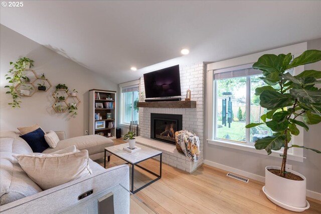 living room featuring light wood finished floors, a brick fireplace, baseboards, recessed lighting, and lofted ceiling