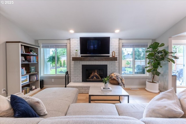 living room featuring wood finished floors, baseboards, a fireplace, and lofted ceiling