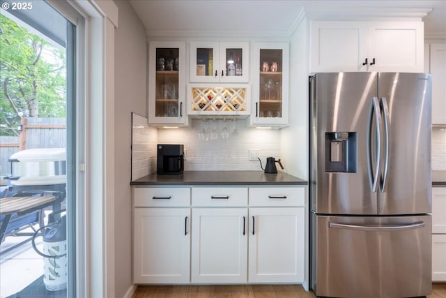 kitchen featuring stainless steel fridge with ice dispenser, dark countertops, and backsplash