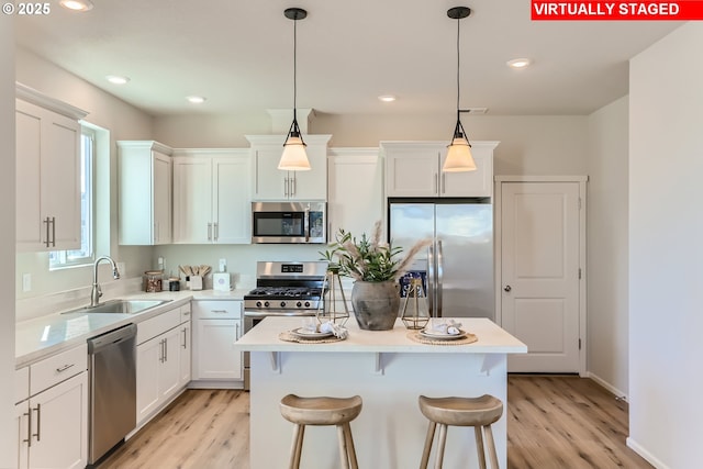 11325 NW Main St, North Plains, OR 97133 - kitchen with stainless steel appliances, a sink, a center island, light wood finished floors, and light countertops