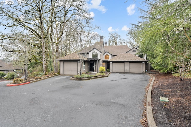 view of front of property featuring aphalt driveway, a garage, and roof with shingles