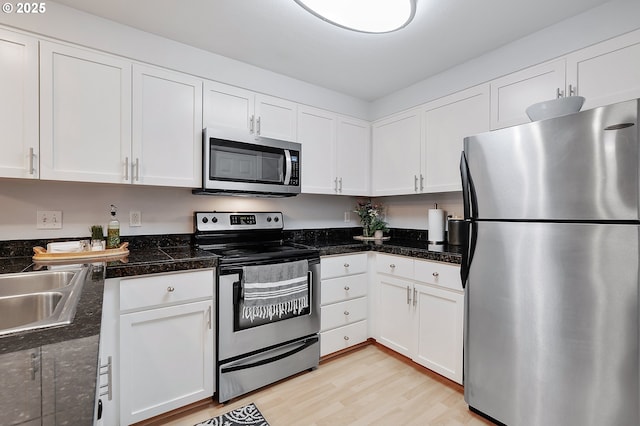 kitchen featuring white cabinetry, tile countertops, light wood finished floors, and appliances with stainless steel finishes