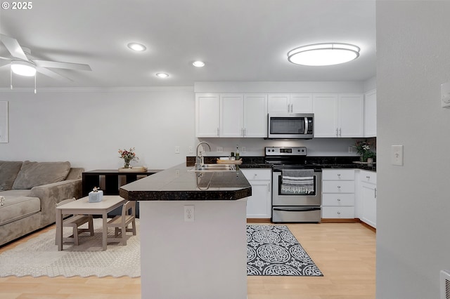 kitchen featuring open floor plan, white cabinets, a peninsula, and stainless steel appliances