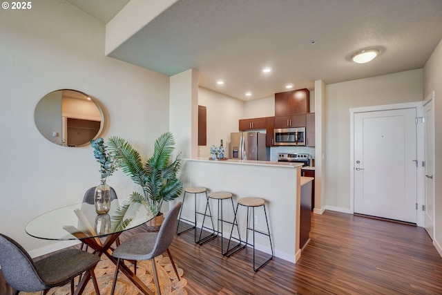 16417 NW Chadwick Way Unit 302, Portland, OR 97229 - kitchen featuring appliances with stainless steel finishes, dark wood-type flooring, a kitchen breakfast bar, a peninsula, and recessed lighting