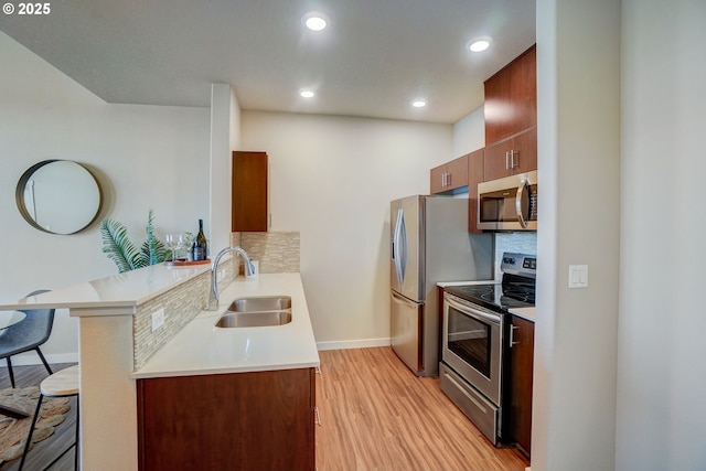 16417 NW Chadwick Way Unit 302, Portland, OR 97229 - kitchen with stainless steel appliances, a kitchen breakfast bar, a peninsula, light wood-style floors, and tasteful backsplash