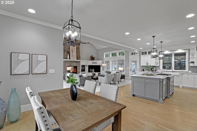 dining area with a notable chandelier, recessed lighting, light wood-type flooring, and a lit fireplace