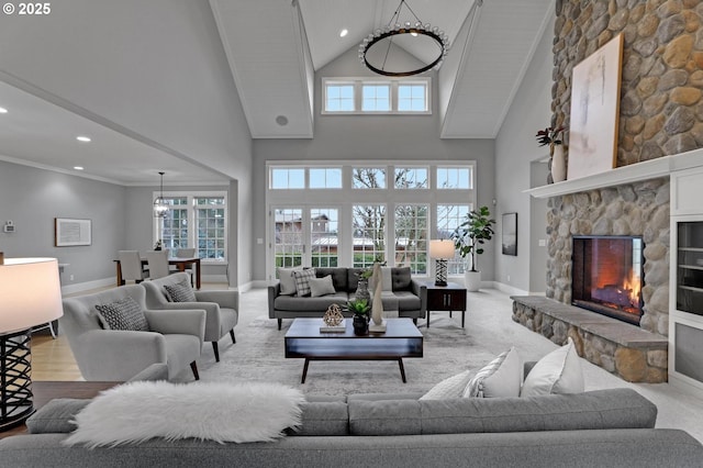 living room featuring baseboards, high vaulted ceiling, recessed lighting, ornamental molding, and a stone fireplace