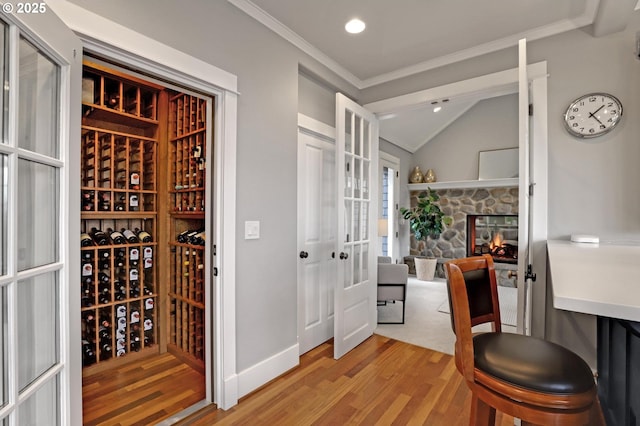 wine area with baseboards, light wood finished floors, lofted ceiling, recessed lighting, and crown molding