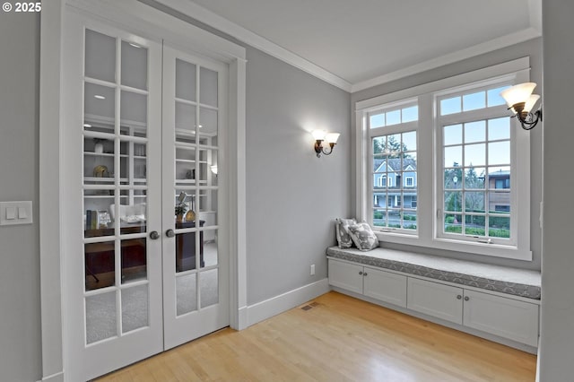 interior space with visible vents, baseboards, light wood finished floors, french doors, and crown molding