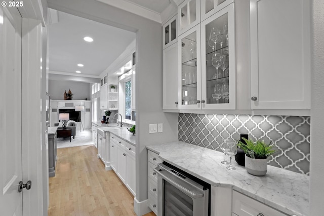 kitchen featuring decorative backsplash, wine cooler, ornamental molding, and white cabinets