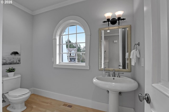 bathroom featuring visible vents, baseboards, toilet, ornamental molding, and wood finished floors