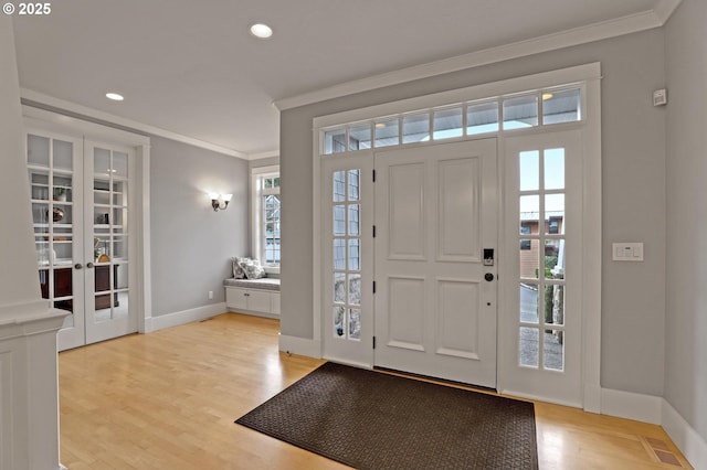 entrance foyer featuring visible vents, baseboards, light wood-style floors, and crown molding