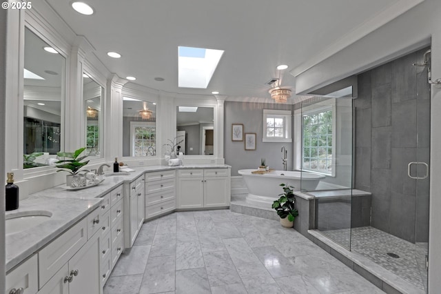 full bathroom featuring a shower stall, double vanity, a skylight, a freestanding tub, and a sink