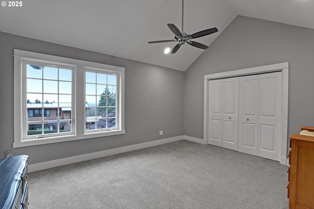 unfurnished bedroom with baseboards, lofted ceiling, carpet flooring, a closet, and a ceiling fan